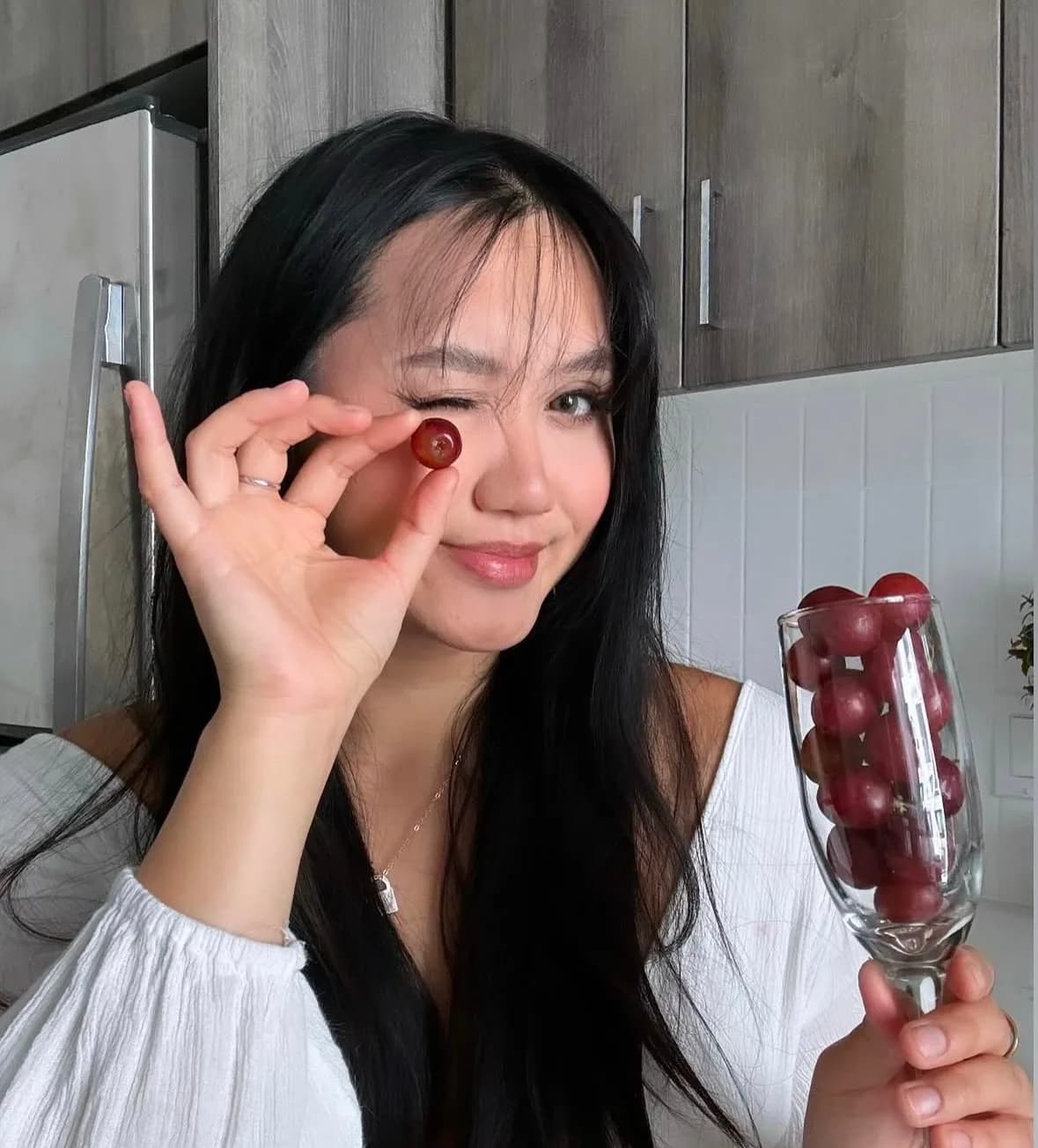 Angela holding a cherry beside a glass